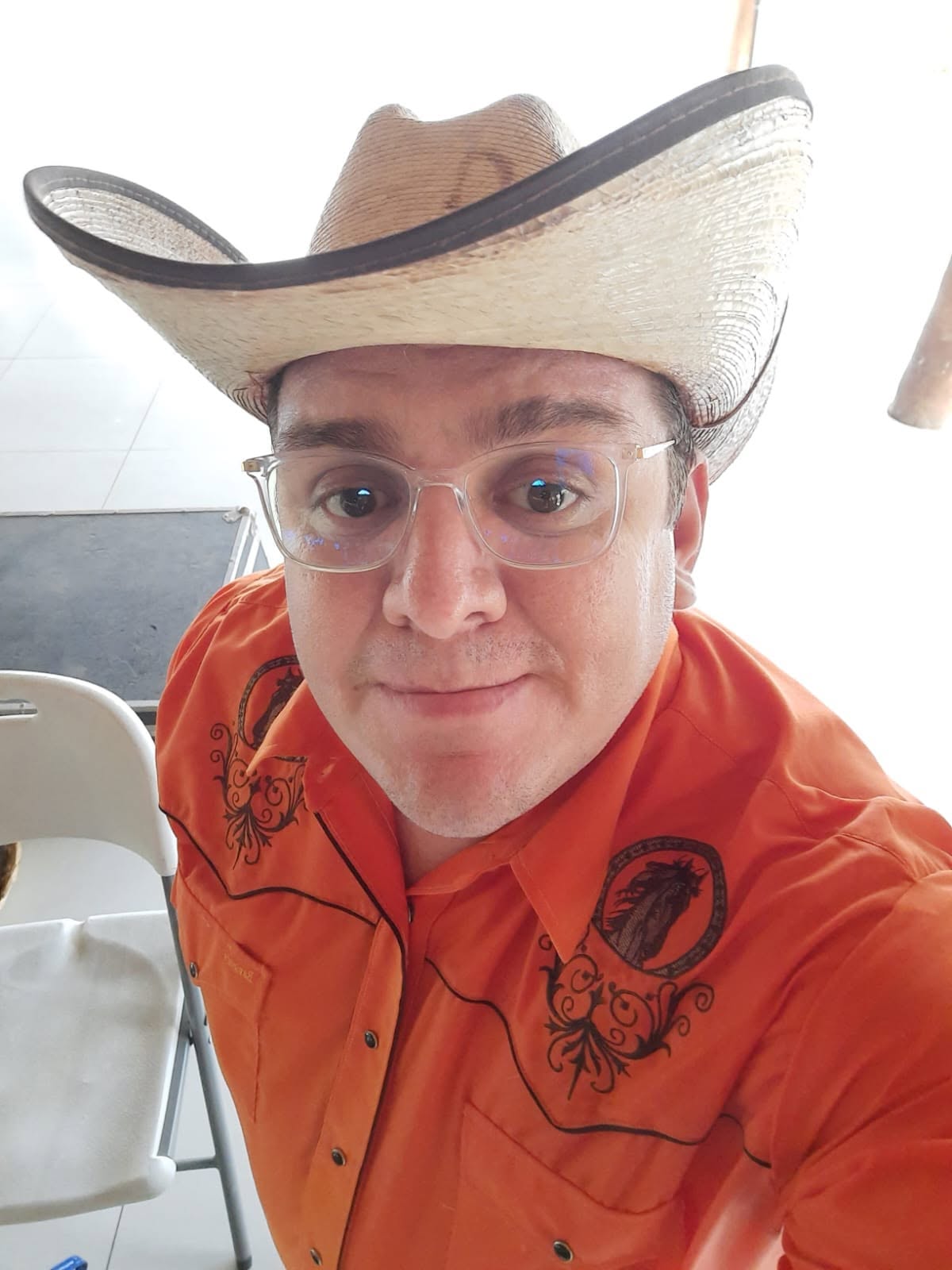 El Cochi con sombrero vaquero y camisa naranja