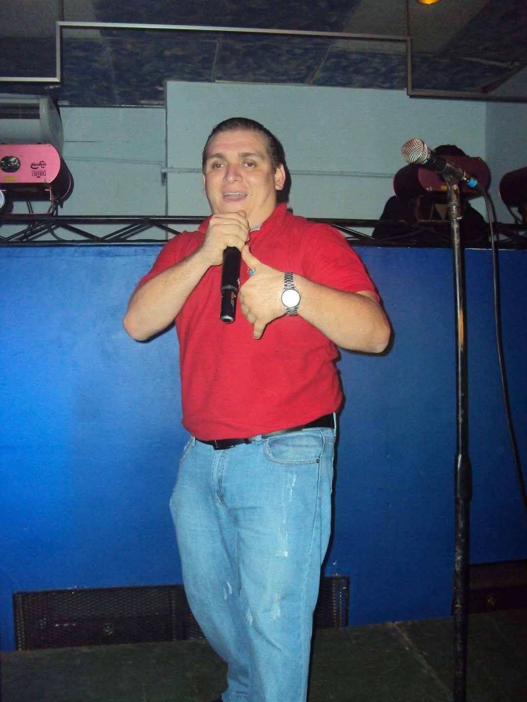 El Cochi en tarima con camisa roja y micrófono